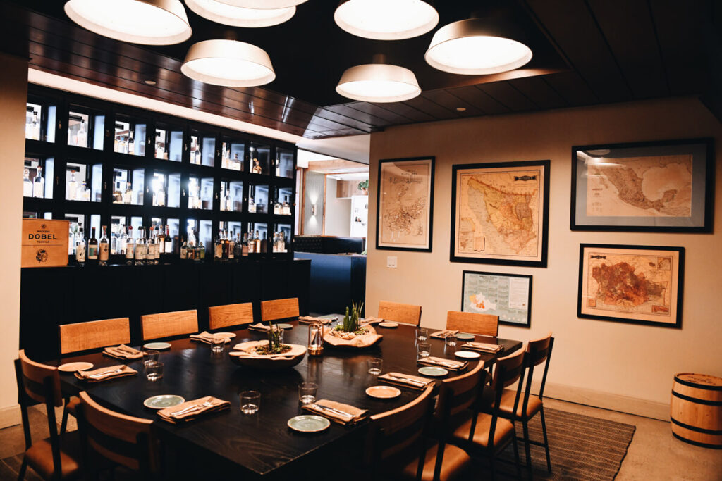 Private dining room with long table and tequila display